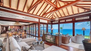 A spacious living area with a large sofa, a dining table, and a view of the ocean. - Hale Ae Kai in Kilauea (Kilauea)