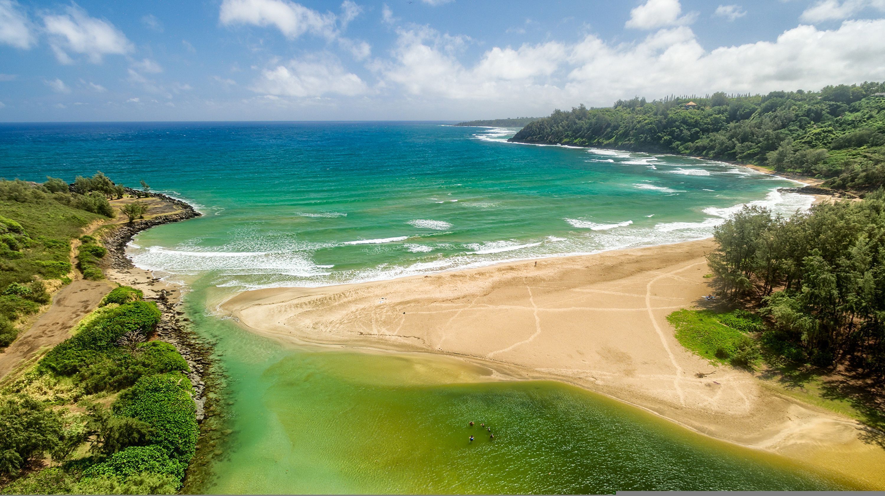 A coastal landscape with a beach, clear waters, and lush greenery.