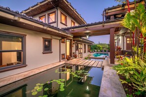 A traditional house with a swimming pool, a covered patio, and a garden with water lilies.