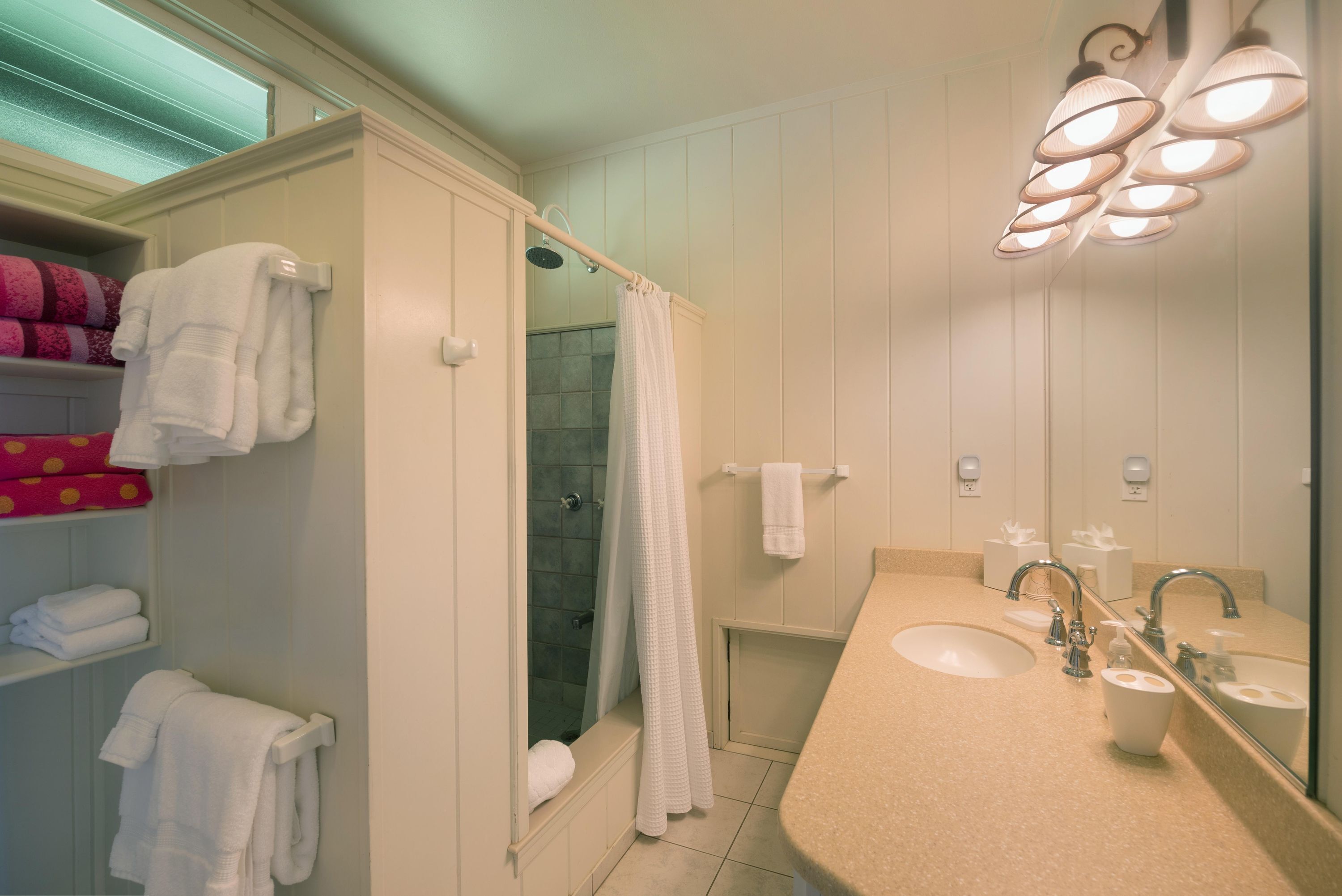 Un baño con ducha, lavamanos y espejo.