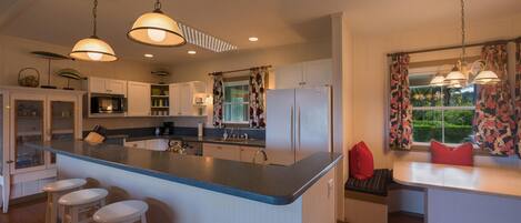 Una cocina moderna con una isla central, taburetes de bar e iluminación colgante.