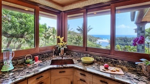 A kitchen with a large window, granite countertop, and wooden cabinets.