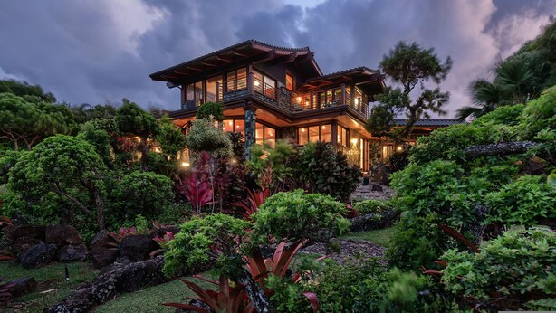 A large, multi-story house with a traditional architectural style, surrounded by lush greenery and a well-maintained garden.