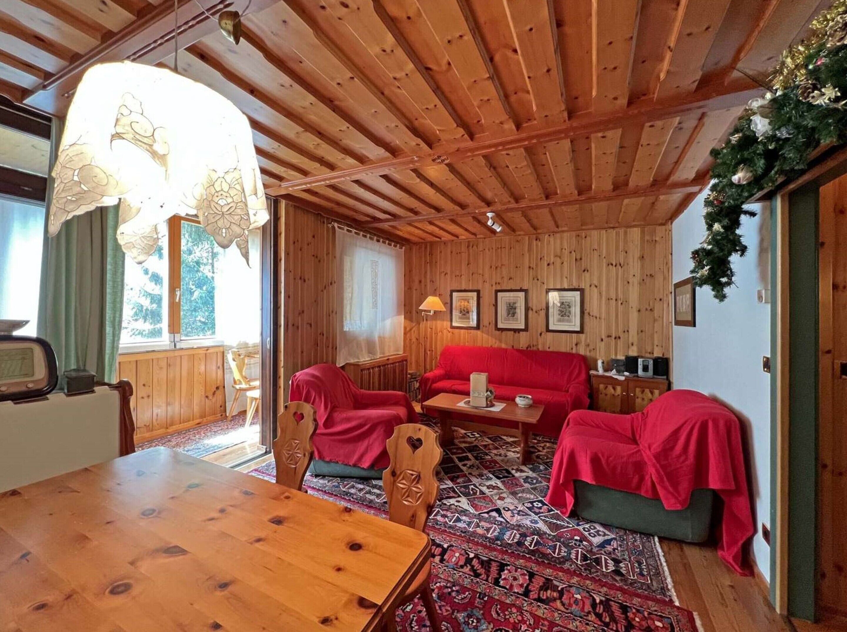 A cozy wooden room with a dining table, two sofas, and a patterned rug.