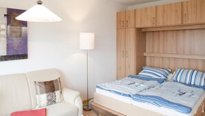 Ein Schlafzimmer mit Bett, Nachttisch, Lampe, Kleiderschrank und einem Bild an der Wand.