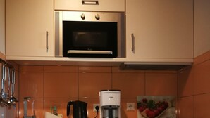Eine Küche mit weißen Schränken, einer Mikrowelle, einer Kaffeemaschine und einer Obstschale.