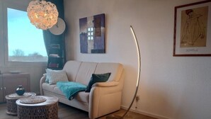 Ein Wohnzimmer mit einer Couch, einem runden Couchtisch, einer Stehlampe und einem Teppich.