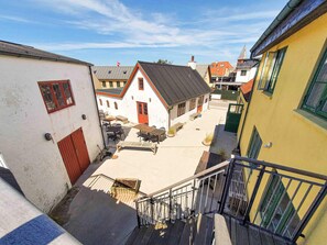 A narrow street with buildings on either side, a staircase leading to a higher level, and outdoor seating areas.
