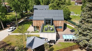 Una casa moderna con un amplio patio, una piscina y un automóvil estacionado en la entrada.