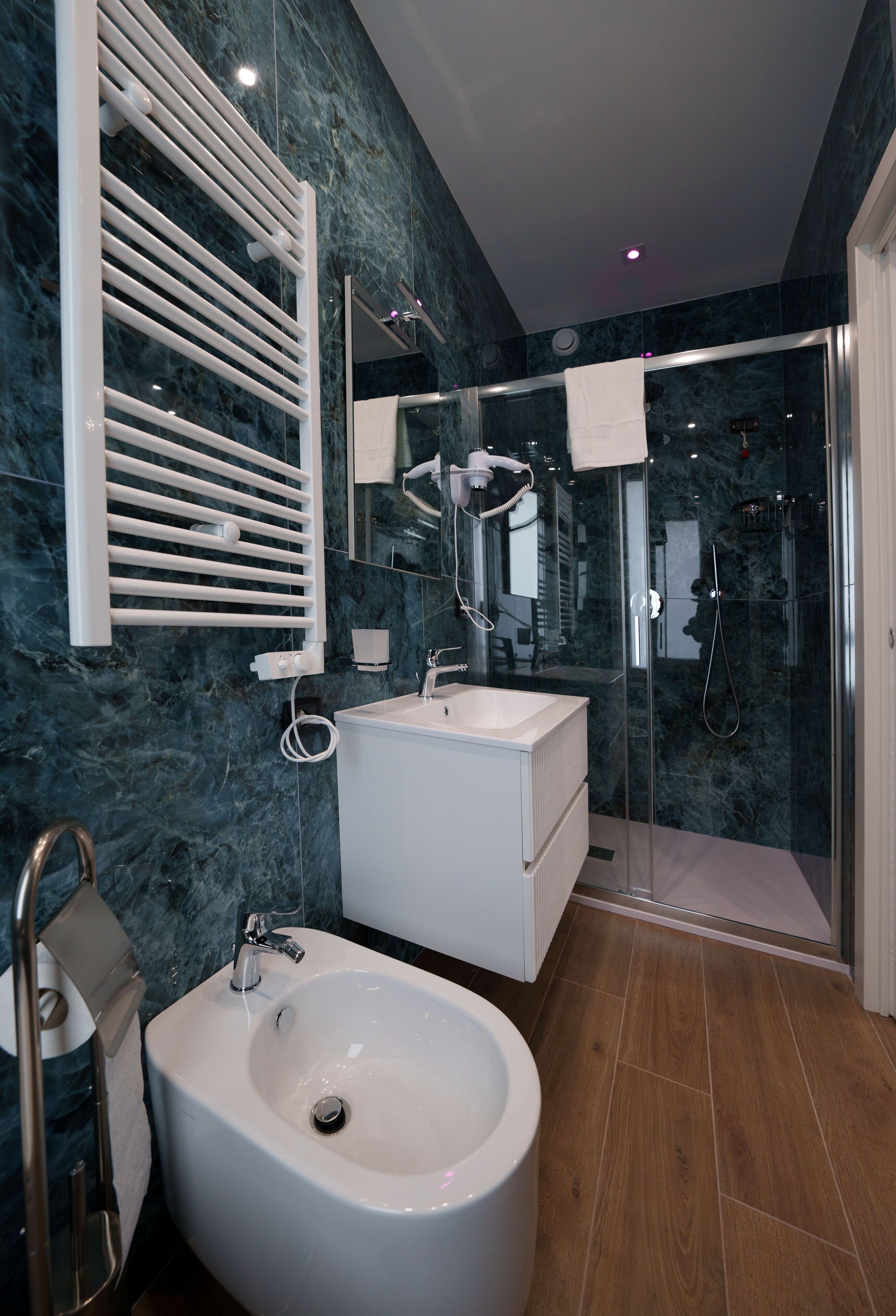Un baño moderno con una bañera independiente, una ducha con mampara de vidrio y un salpicadero de mármol.