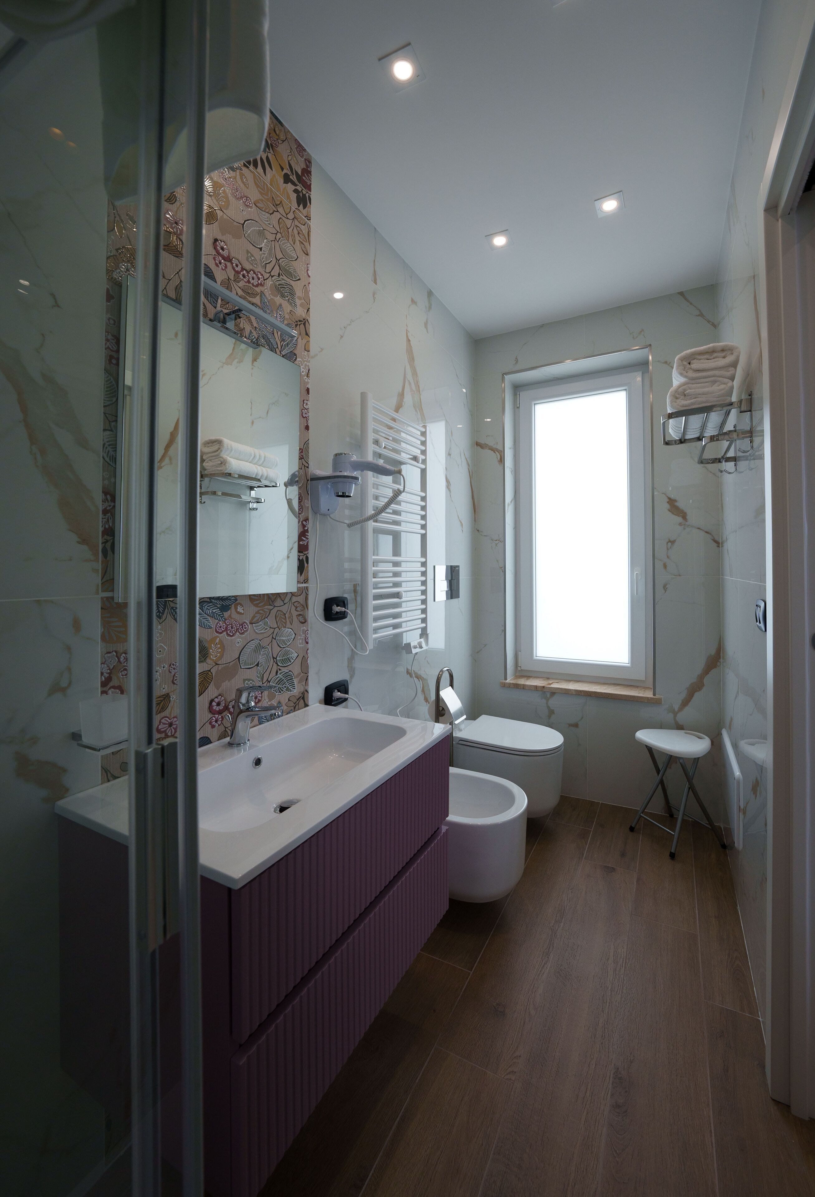 Une salle de bain avec un grand miroir, une baignoire, des toilettes et une fenêtre.