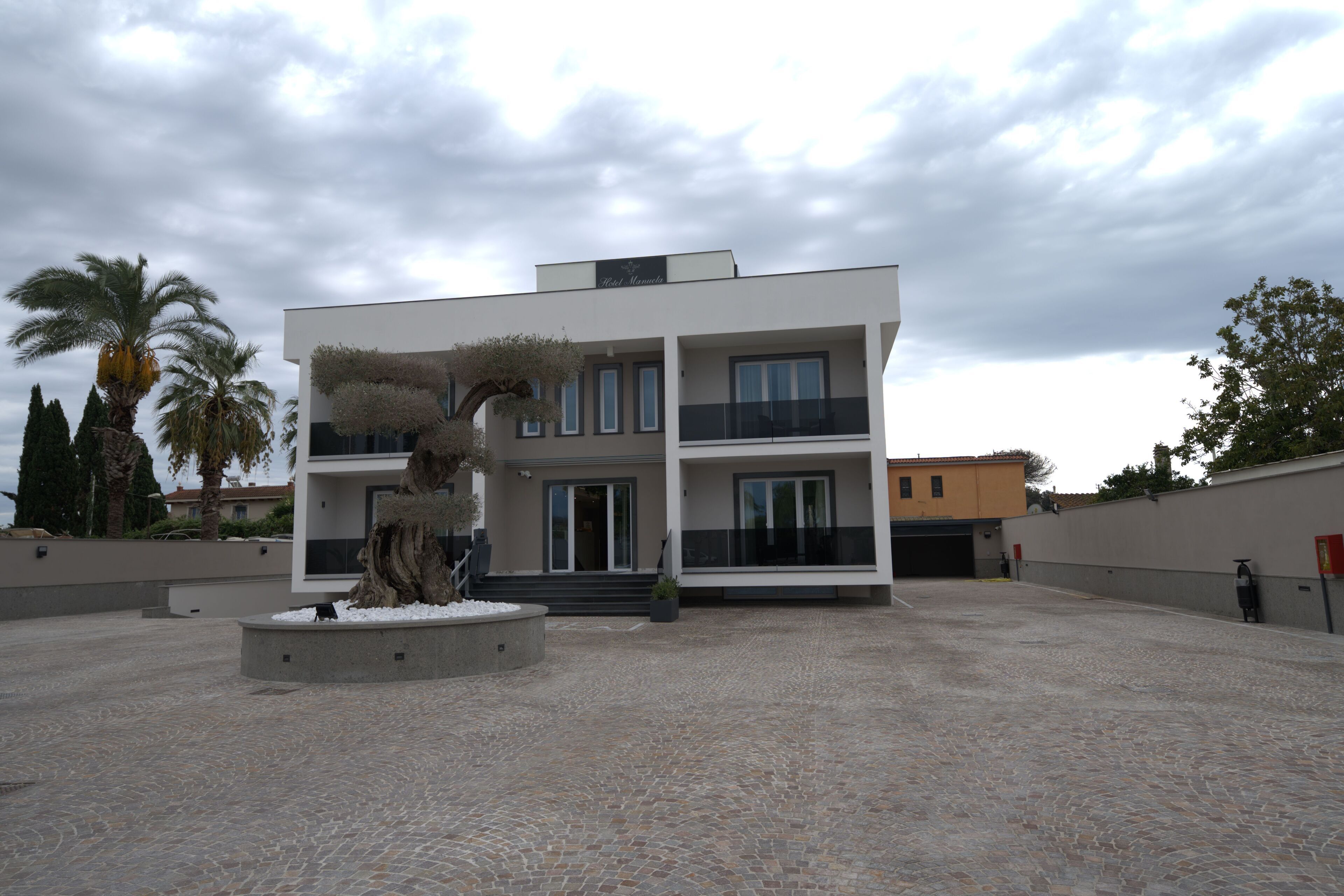 A modern two-story building with a flat roof, large windows, and a balcony.