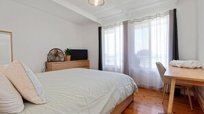 Relax in a spacious room with a large bed, TV, and a small table.