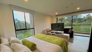 Une chambre d’hôtel moderne dotée d’un grand lit, d’une télévision et d’un balcon offrant une vue sur l’extérieur.