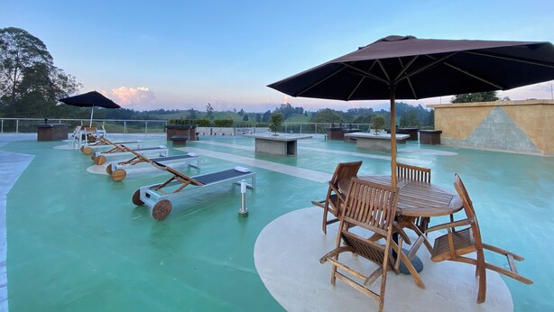 Un espace piscine aménagé sur le toit, avec des chaises longues, une table et des parasols.