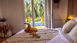 A bedroom with a bed, a view of an outdoor pool, and a table with a floral tablecloth. - Douceur Des Mées (Les Mees)