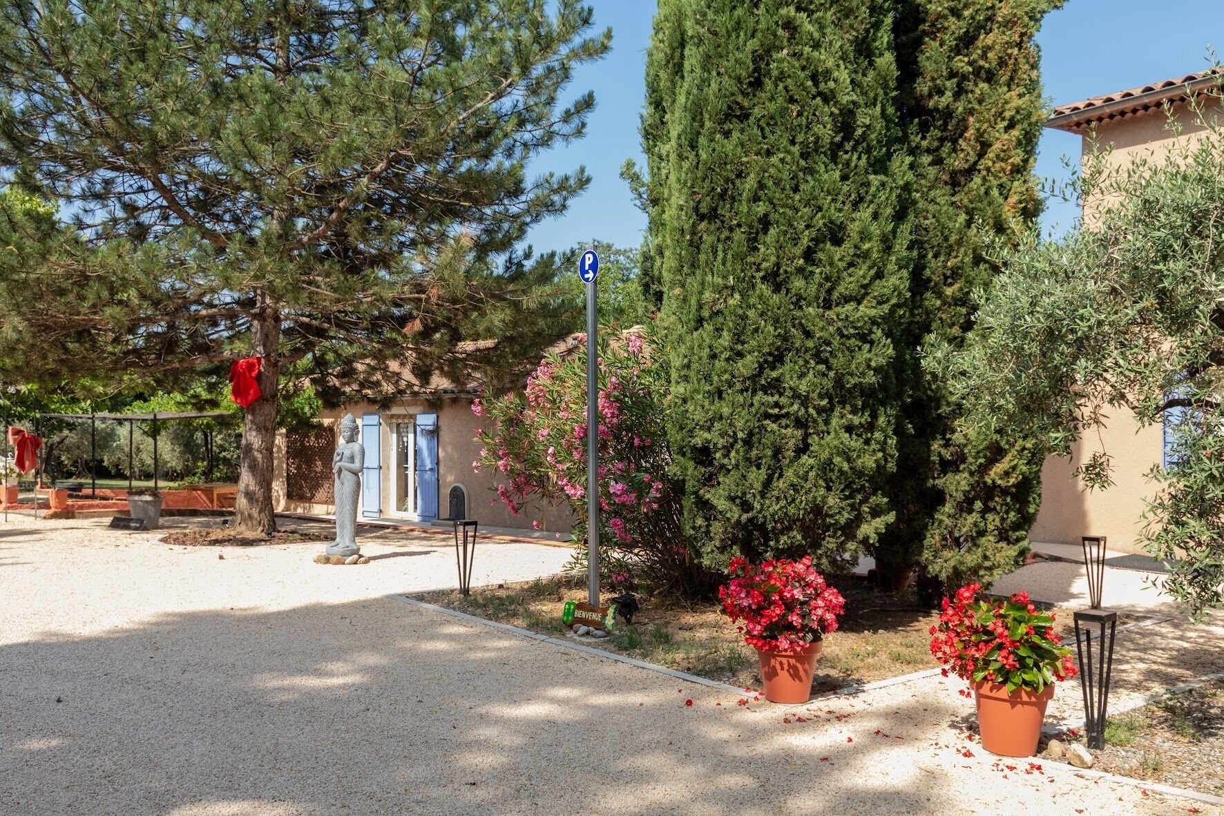 A courtyard with a statue, potted plants, and a building with blue shutters.