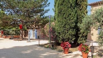 A courtyard with a statue, potted plants, and a building with blue shutters.
