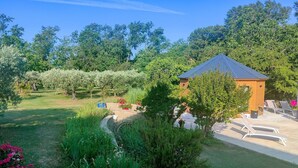A garden with a small wooden structure, possibly a gazebo, surrounded by lush greenery and flowering plants. - Douceur Des Mées (Les Mees)
