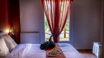 Habitación de hotel con cama, almohada con forma de cisne, toalla con forma de cisne y ventana con vistas a zonas verdes.