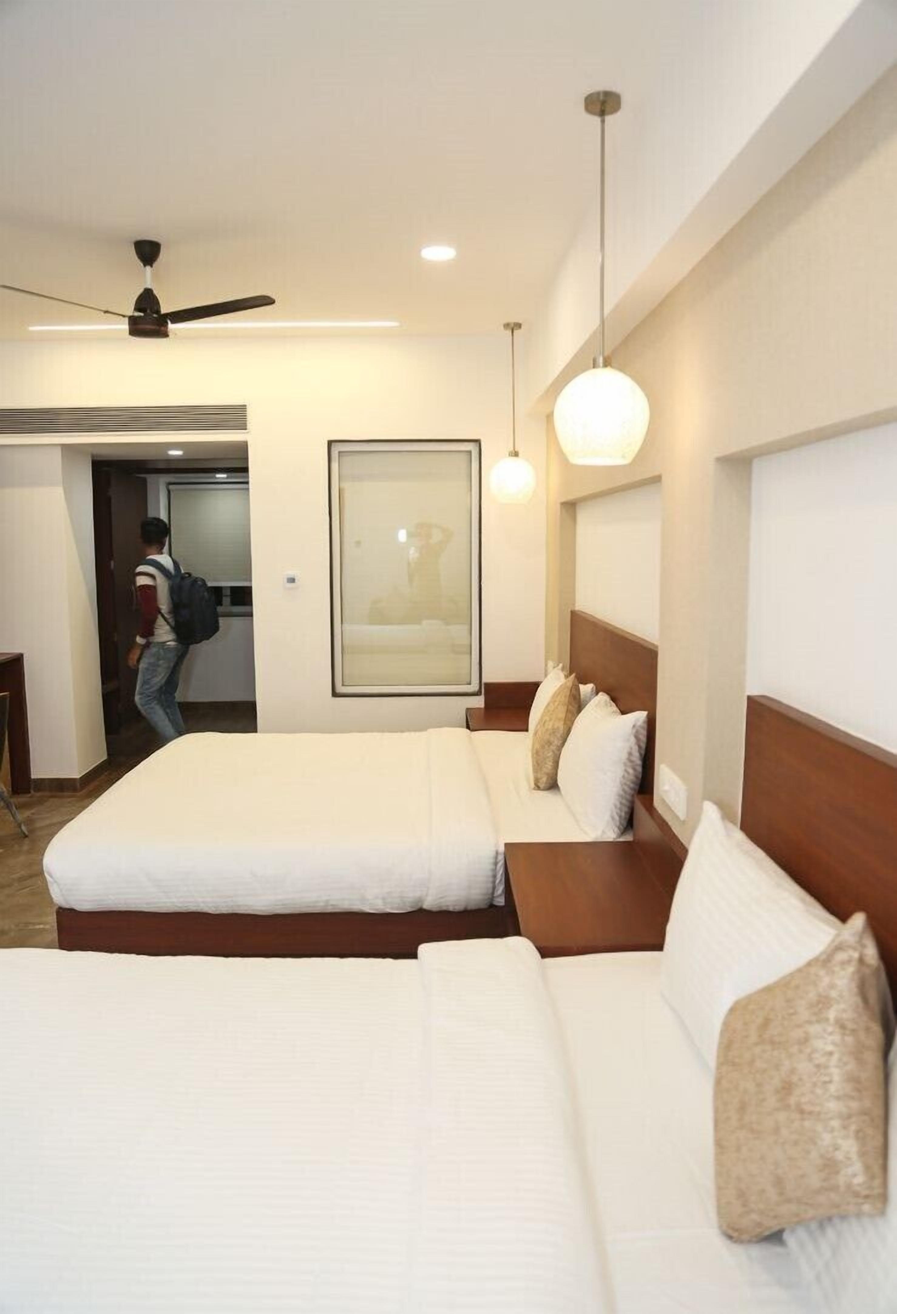 A hotel room with two beds, a ceiling fan, and a framed picture on the wall.