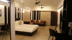 A modern hotel room with a large bed, a sofa, a desk, and a wardrobe. - hotel kadamb tree (Jabalpur)
