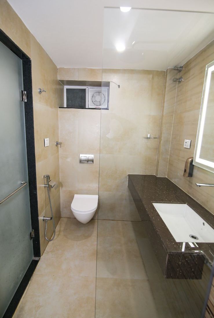 A modern bathroom with a glass-enclosed shower, a white toilet, and a marble countertop with a sink.