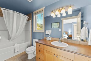 A bathroom with a bathtub, toilet, sink, and a large mirror. - Ocean View 2 Bedroom Pet Friendly Townhome, Sooke, BC (Sooke)