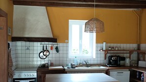 Eine Küche mit Holztisch, zwei Stühlen, einem Herd, einer Spüle und einem Fenster mit Aussicht.