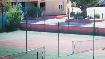 Una cancha de tenis con una red, rodeada por una valla.