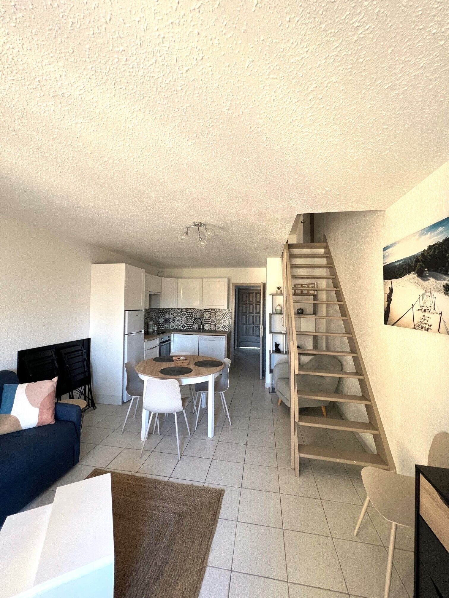 A compact living space with a kitchenette, a dining area, and a staircase.