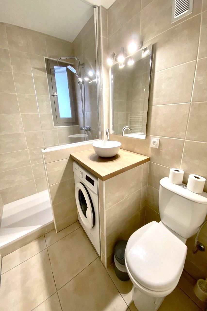 Un baño con lavamanos, inodoro y lavadora.
