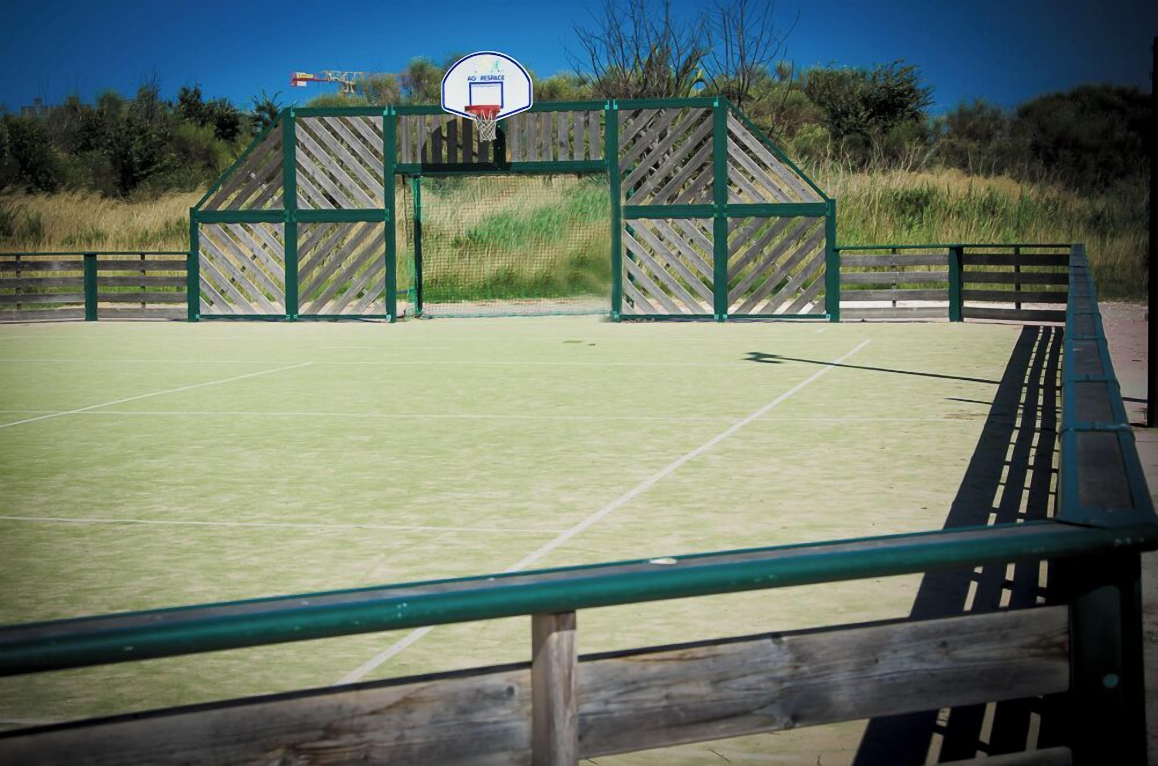 Een buitenbasketbalveld met een houten omheining en een basketbalring.