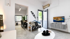 Una sala de estar moderna con un sofá blanco, una mesa de comedor y un televisor montado en la pared.