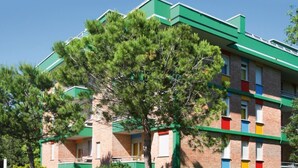 Un edificio de varios pisos con techo verde y fachada de ladrillo, con balcones y barandillas de colores.