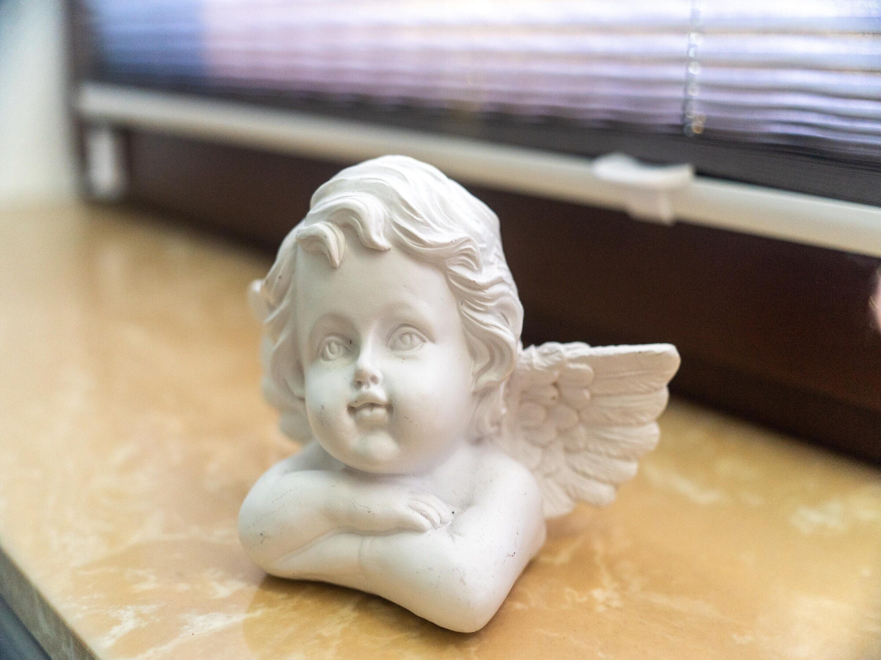 Une statue d’ange blanche, posée sur une surface de marbre.