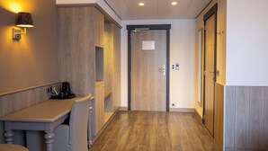 A hotel corridor with a wooden floor, a reception desk, and a door with a sign. - Blanckthys Hotel (Voeren)