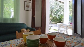 A dining area with a table set for four, a green sofa, and a view of the garden through the door.