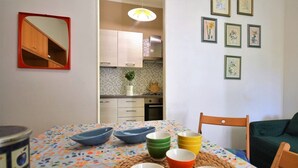 A dining area with a table set for four, a mirror, and a kitchen in the background.