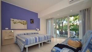 Un dormitorio con cama, sofá, escritorio y ventana con vistas al exterior.