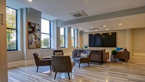 A spacious living room with large windows, a flat-screen TV, and modern furniture. - XL Studio - Metro Studio, Chic Stay (Philadelphia)