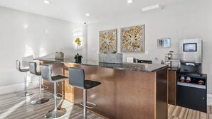 A modern kitchen with a central island, bar stools, a coffee machine, and artwork on the walls. - XL Studio - Metro Studio, Chic Stay (Philadelphia)