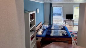 Ett sovrum med en säng, ett skrivbord, en tv och en balkong med utsikt.