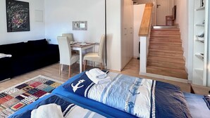 Ett sovrum med en säng, ett skrivbord och en stol. En trappa leder upp till en övre våning.