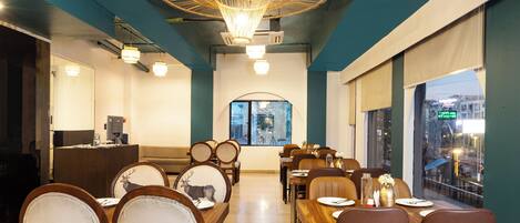 A restaurant with a long dining area, wooden tables, and chairs.