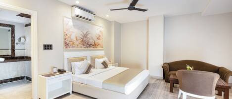 Een moderne slaapkamer met een bed, nachtkastjes, een plafondventilator, een airconditioningsysteem, een bank en een stoel.