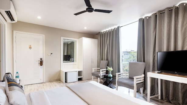 Una habitación de hotel moderna con cama, televisión, escritorio y silla.