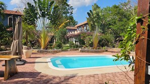 A swimming pool surrounded by lush greenery and a stone pathway. - Villa Ataraxia Solferino  (Solferino)