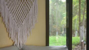 Un lit recouvert d’une couvre-lit à motifs bleus et blancs, avec deux oreillers et une décoration murale en macramé.