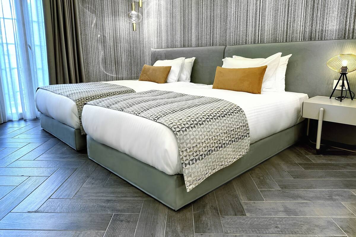 A modern hotel room with a large bed, a bedside table with a lamp, and a textured wall.